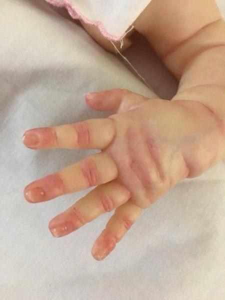 Detalhe da mãozinha de uma bebê reborn com veias e unhas pintadas
